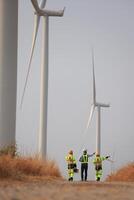 Specialist wind turbine Team of Engineers discussing Green Energy Production in Wind Turbines Farm photo