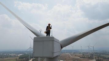 Specialist windmill engineer with green safety jacket and full PPE include safety harness work on top of wind turbine photo