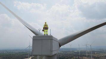 Specialist windmill engineer with green safety jacket and full PPE include safety harness work on top of wind turbine photo