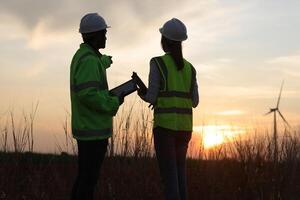 Silhouette a couple of electrical engineer working at windmill field. ecology energy renewable alternative green power environment factory concept photo