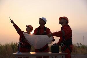 Portrait Windmill engineer team with red work uniform with safety hard hat and harness work in wind turbine farm photo