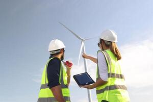 Wind turbine engineers working on the roof of car at a wind turbine field, checking and comparing the blueprint and condition of the Turbine's Electrical Power photo