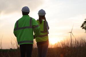 Silhouette a couple of electrical engineer working at windmill field. ecology energy renewable alternative green power environment factory concept photo