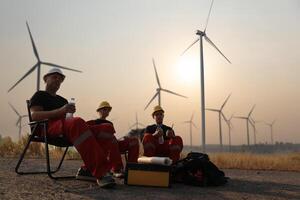 retrato molino ingeniero equipo con rojo trabajo uniforme con la seguridad difícil sombrero y aprovechar trabajo en viento turbina granja foto