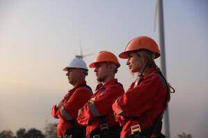 retrato molino ingeniero equipo con rojo trabajo uniforme con la seguridad difícil sombrero y aprovechar trabajo en viento turbina granja foto