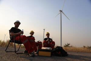 Portrait Windmill engineer team with red work uniform with safety hard hat and harness work in wind turbine farm photo