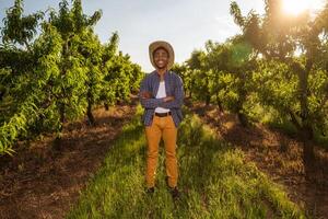 retrato de afroamericano granjero en su huerta. él es cultivando ciruela. foto