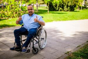 retrato de contento hombre en silla de ruedas. él es disfrutando soleado día en ciudad parque. foto