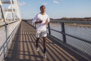 joven afroamericano hombre es trotar en el puente en el ciudad. foto