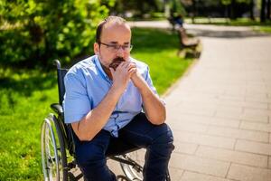 Close up portrait of man in wheelchair. He is worried and thoughtful. photo