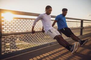 Two african-american friends are exercising on the bridge in the city. They are doing reverse push-ups. photo