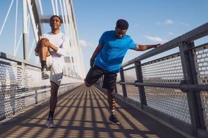 Two african-american friends are exercising on the bridge in the city. They are warming up for jogging. photo