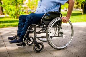 Close up image of man in wheelchair rolling on pathway in park. photo