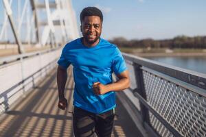 joven afroamericano hombre es trotar en el puente en el ciudad. foto