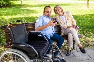 hombre en silla de ruedas es gasto hora con su madre en parque. foto