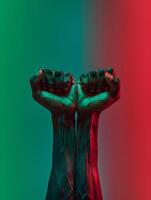 Black men's fists held up with green and red gradient colors. Black history, slavery , freedom background. photo