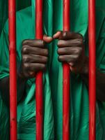 Hands of an African man holding red prison bars. Unity, black history month background. photo