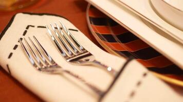 round bowl or ceramic plate and forks on napkin on wooden table. video