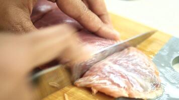 using knife slicing a fresh fish on wooden chopping board . video