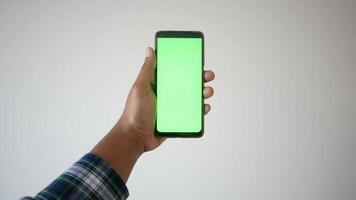 pov coup de Jeune homme main en portant intelligent téléphone avec vert écran contre une blanc mur video