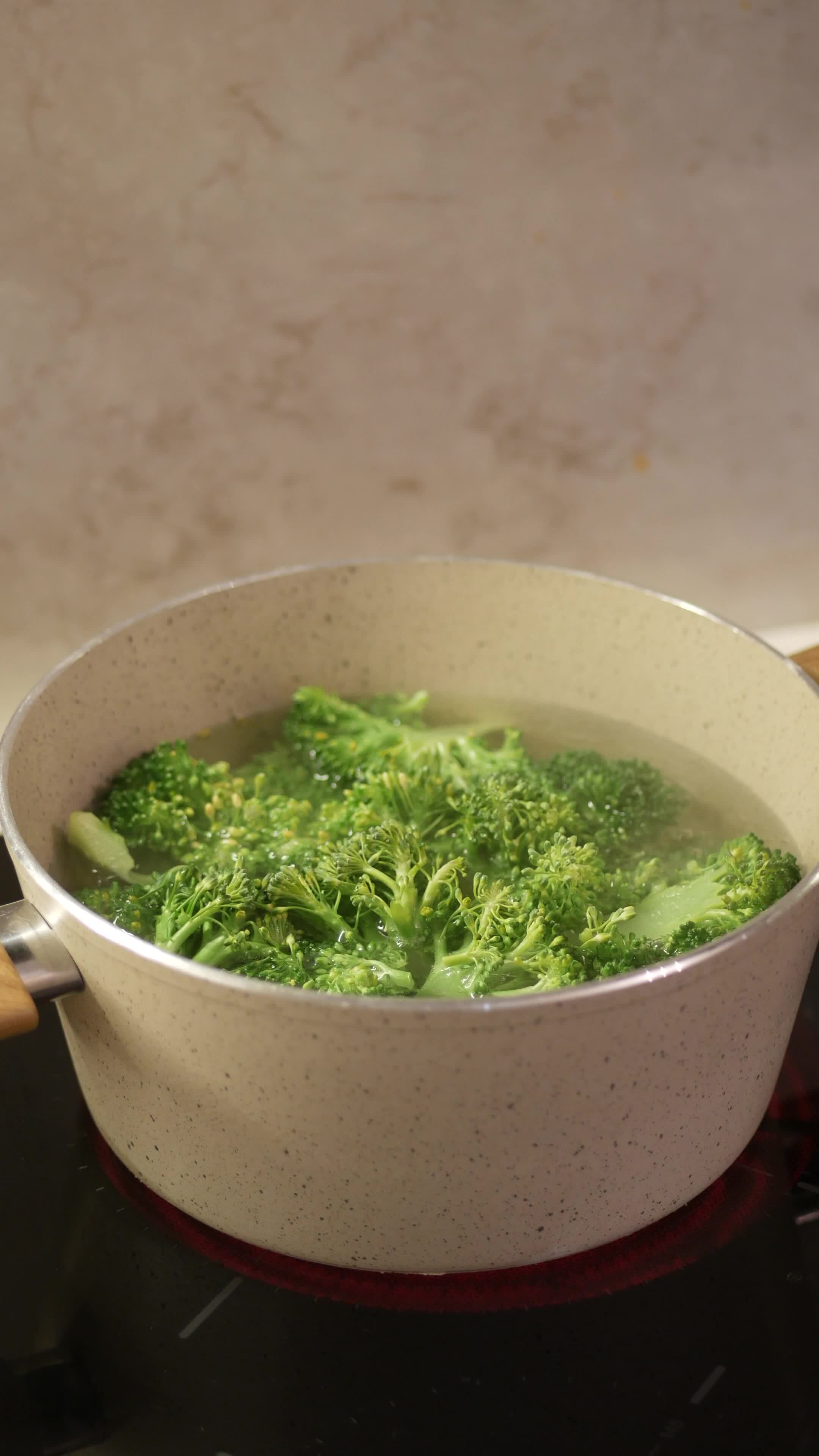 Fresh green broccoli florets gently boiling in a pot of water, 45373000