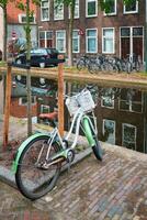 Bicycle parked near the canal in Delft street with old houses. Delft, Netherlands photo