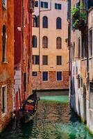 Narrow canal with gondola in Venice, Italy photo