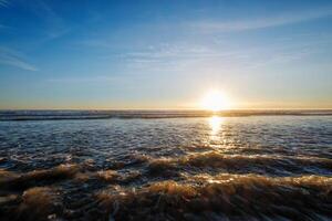 atlántico Oceano puesta de sol con surgiendo olas a fonte da telha playa, Portugal foto