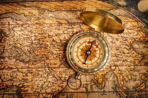 Old vintage golden compass on ancient map photo