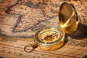 Old vintage golden compass on ancient map photo