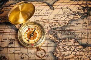 Old vintage golden compass on ancient map photo