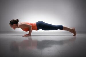 Woman practices yoga asana Chaturanga Dandasana photo