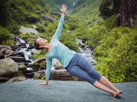 Woman doing yoga asana Vasisthasana - side plank pose outdoors photo