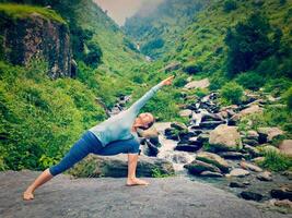 Woman practices yoga asana Utthita Parsvakonasana outdoors photo