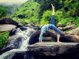 Woman doing yoga asana at waterfall photo