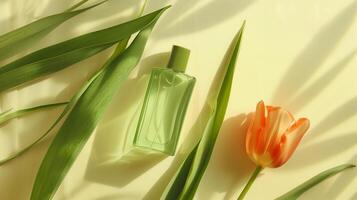 A bottle of green oil is placed on the long leaves, with an orange tulip next to it. photo