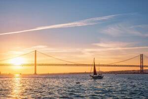 View of 25 de Abril Bridge over Tagus river on sunset. Lisbon, Portugal photo