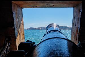 View out of a gunport in hull of the ship on the gun deck over the gun cannon muzzle in photo