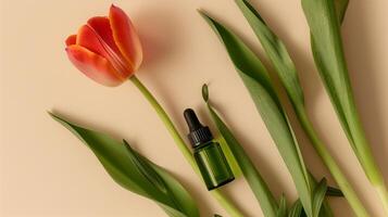 A bottle of green oil is placed on the long leaves, with an orange tulip next to it. photo