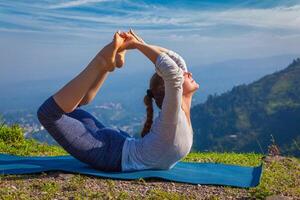 Woman doing Ashtanga Vinyasa Yoga asana Dhanurasana bow pose photo