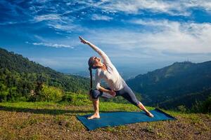 Woman practices yoga asana Utthita Parsvakonasana outdoors photo