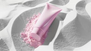 A pink skincare tube lying in white sand. photo