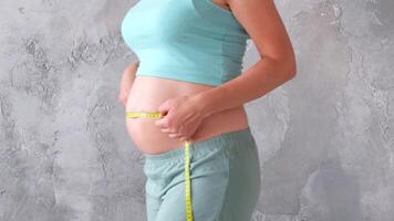 uma grávida mulher medindo dela estômago com medindo fita video