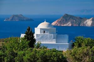 View of Milos island and Greek Orthodox traditional whitewashed church in Greece photo