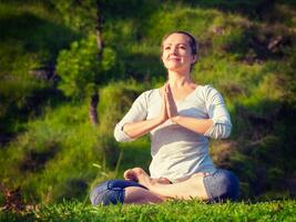 Young sporty fit woman doing yoga Lotus pose oudoors photo