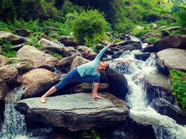 Woman practices yoga asana Utthita Parsvakonasana outdoors photo