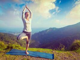 mujer en yoga asana vrikshasana árbol actitud en montañas al aire libre foto