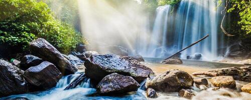 Tropical waterfall in jungle with sun rays photo