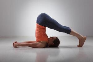 Sporty woman practices yoga asana Halasana photo