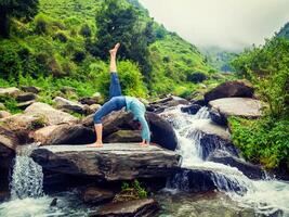 Woman doing yoga asana at waterfall photo